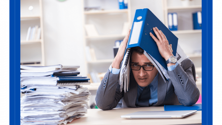 male office worker at a paper filled desk hiding under an open file folder. very stressed