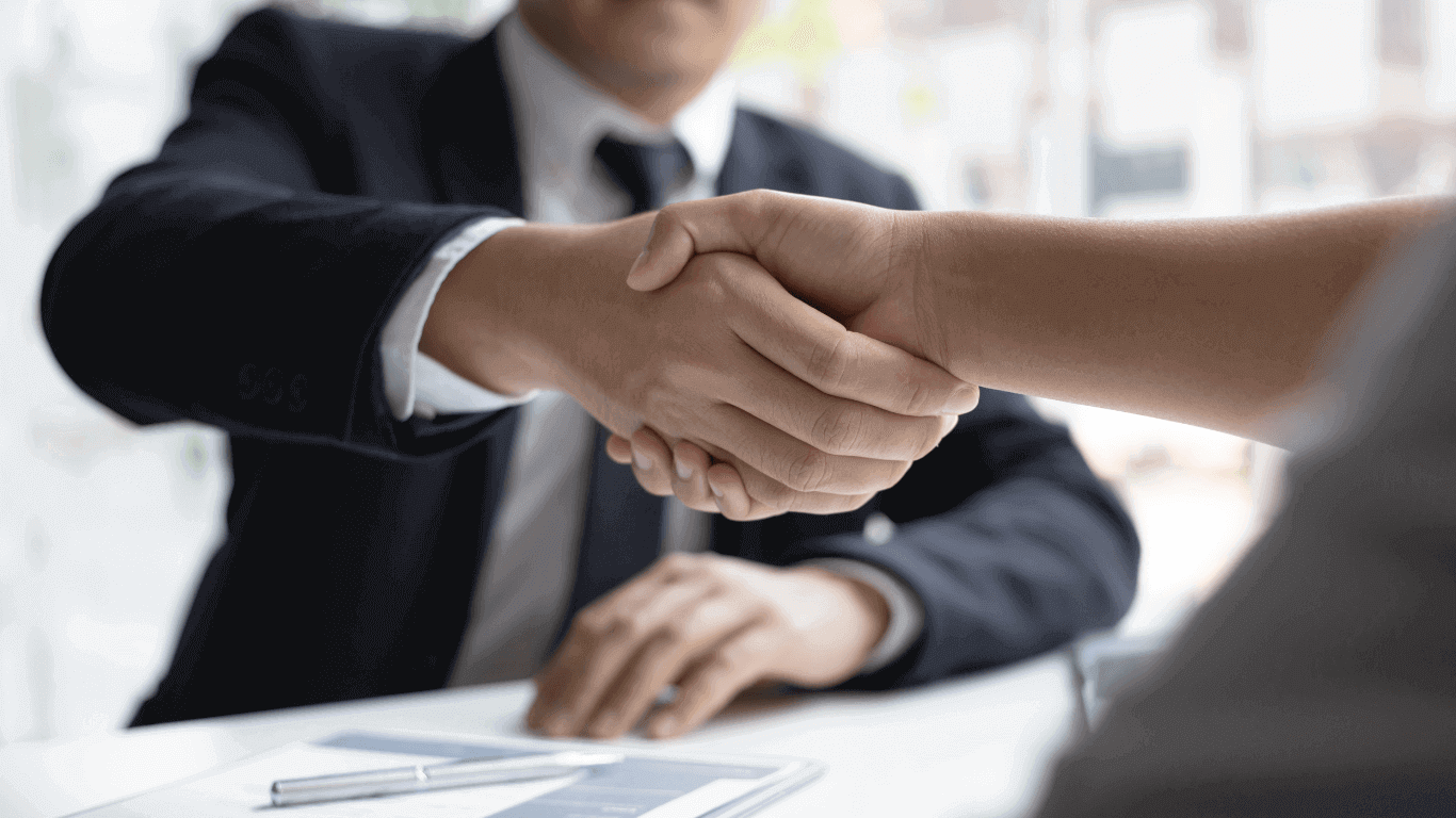 the handshake between a blue-collar worker and a corporate officer dressed in a dark blue suit.